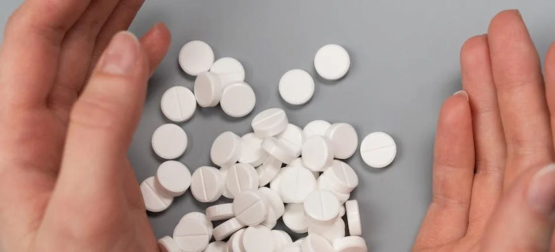 White circular spa tablets scattered on a gray surface with hands visible on either side.