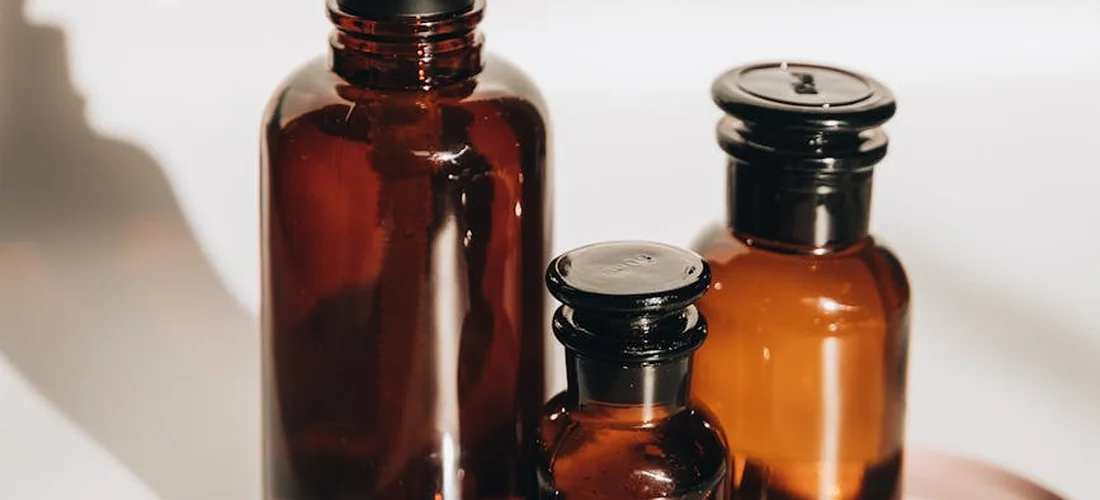 Three amber glass bottles of essential oils on a light surface