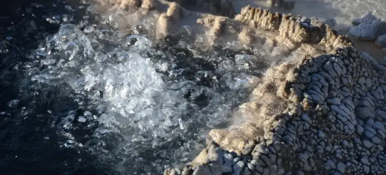 Close-up view of bubbling hot tub water with rugged stone surroundings, evoking a spa setting.