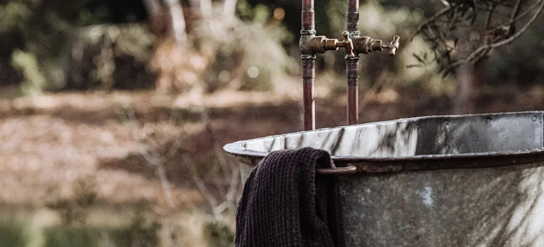 Close-up of a metal hot tub with exposed plumbing and a dark towel draped over the rim, ready for hands-on inspection