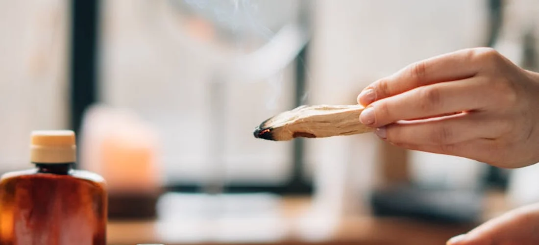 A hand holds a cinnamon stick beside an amber essential oil bottle, illustrating safe oil mixing for DIY hot tub aromatherapy.