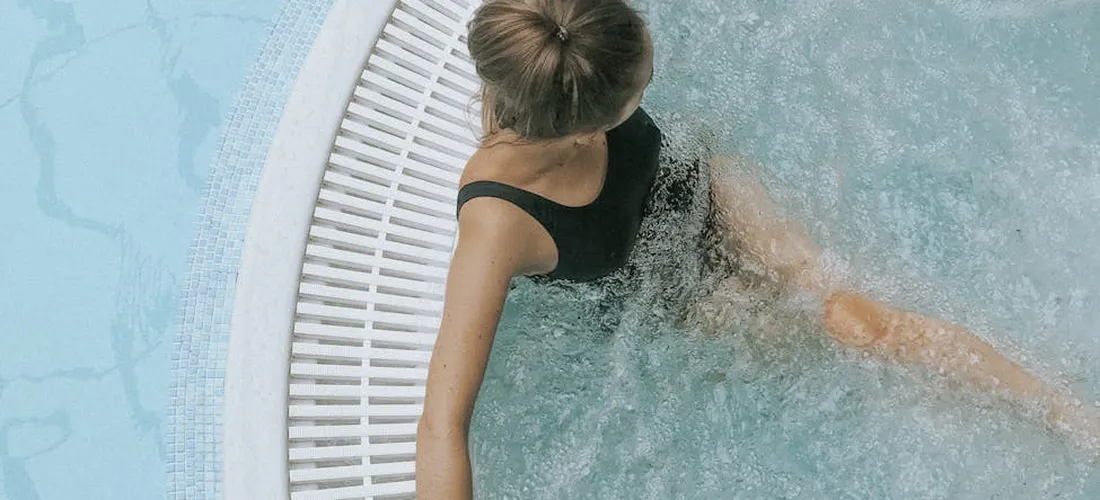 Top-down view of a person in a circular hot tub with bubbles along the edge.