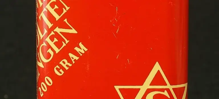 Close-up of a red cylindrical container with white lettering and a geometric star-like symbol on a dark background.