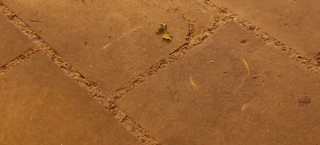 Close-up of brown stone pavers with grout lines, showing a flat surface suitable for observing potential runoff paths.