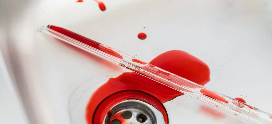 Close-up of a hot tub drain with a red stopper and water droplets.