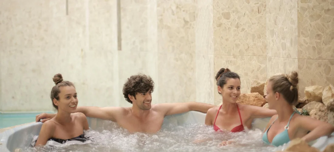 Four people relaxing in a hot tub, smiling and chatting as the water heats.