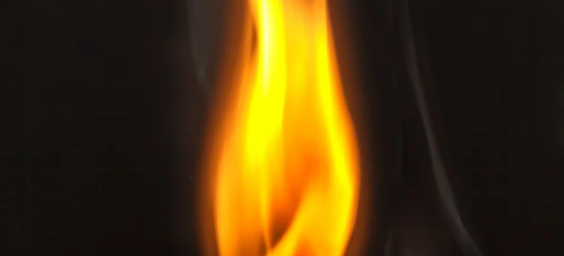 Close-up of a bright orange-yellow flame against a dark background, representing traditional gas heating.