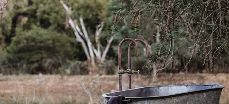 Outdoor metal tub with exposed plumbing in a grassy yard, ready for initial hot tub setup