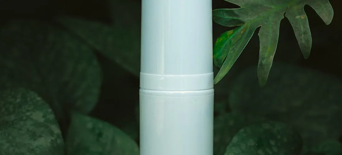 Close-up of a white plastic pipe fitting with green foliage in the background, illustrating spa maintenance components