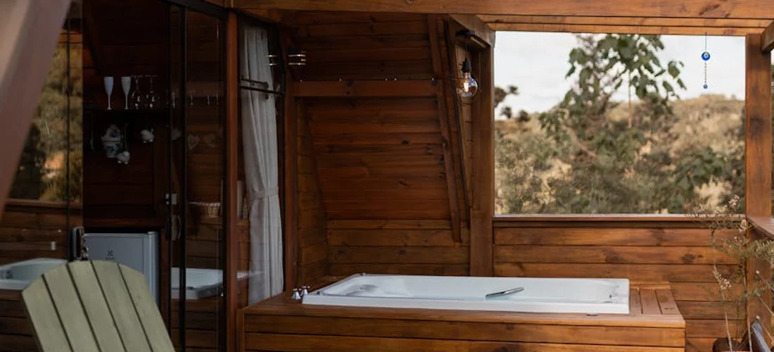 Hot tub installed on a wooden deck under a covered patio, with built-in steps and surrounding wood siding