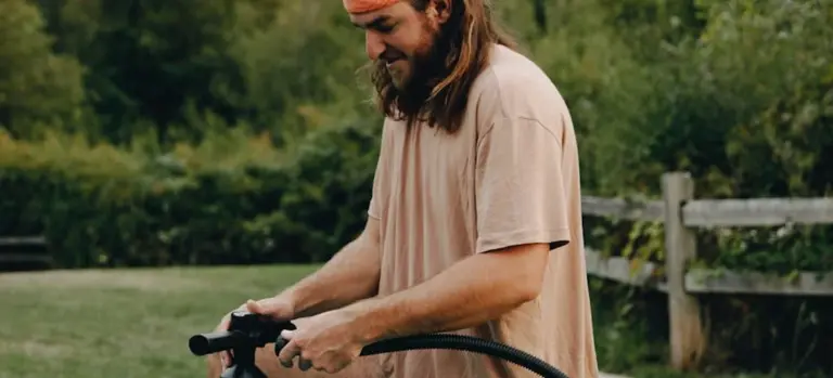Person outdoors handling a hose, preparing to prime a pump.