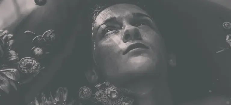 Grayscale image of a person relaxing in a hot tub, with their face above the water and surrounded by bubbles.