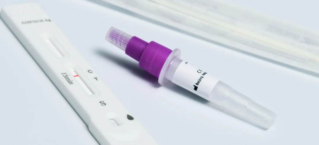 Close-up of a hot tub water test kit: a white strip tester and a purple-capped dropper on a pale surface.