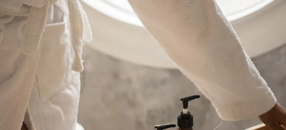 Close-up of a person in a bathrobe near a hot tub faucet, preparing for maintenance.