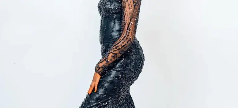 Side view of a person wearing a dark, sequined gown; the dress appears wet and clings to the body.