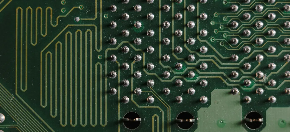 Close-up of a green circuit board with copper traces and solder joints, symbolizing the wiring complexity of hot tub installation.
