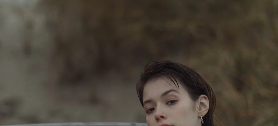 Close-up of a woman with wet hair partially submerged in water, suggesting a hot tub setting.