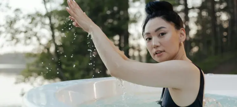 Woman relaxing in an outdoor hot tub with water droplets mid-splash.