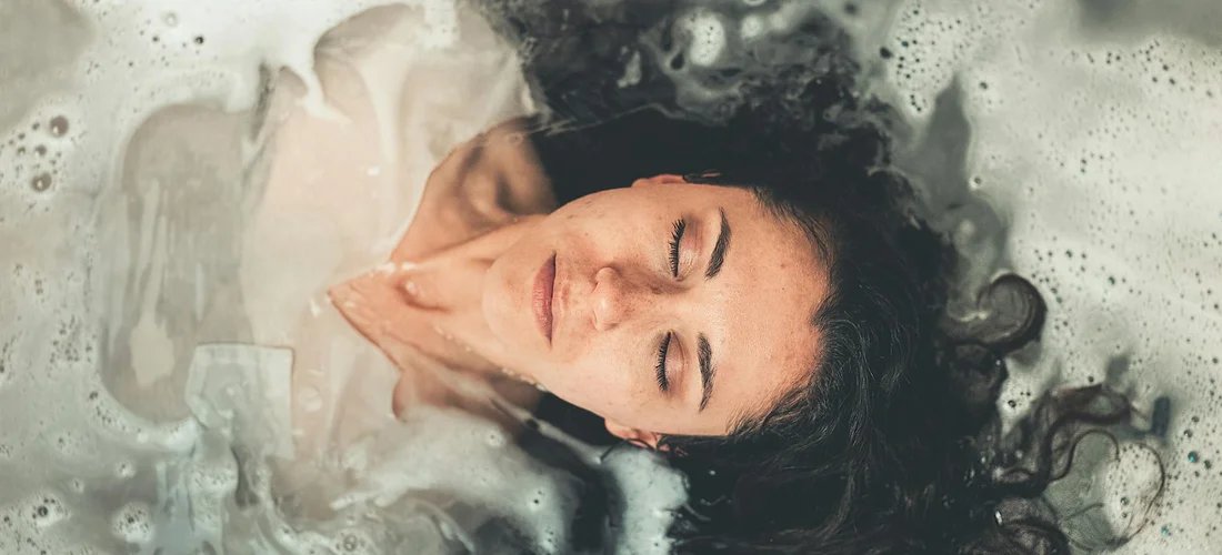 Person relaxing in a foamy hot tub