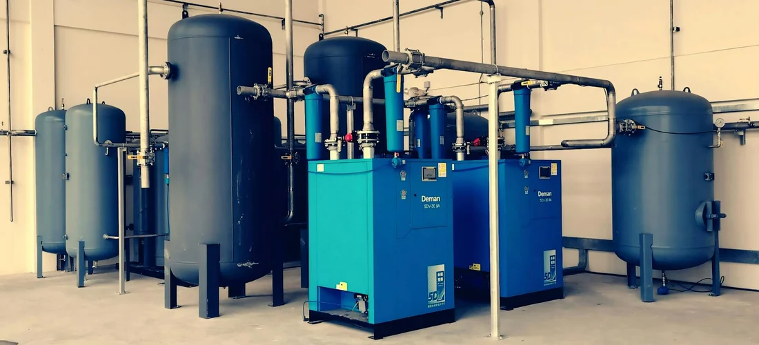 Industrial mechanical room with blue pumps, tanks, and interconnected piping