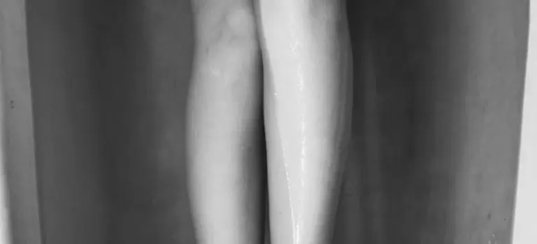 Close-up of a person’s legs soaking in a hot tub, shown in black and white.