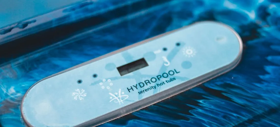 Close-up of a blue HydroPool Serenity hot tub control panel floating on water.