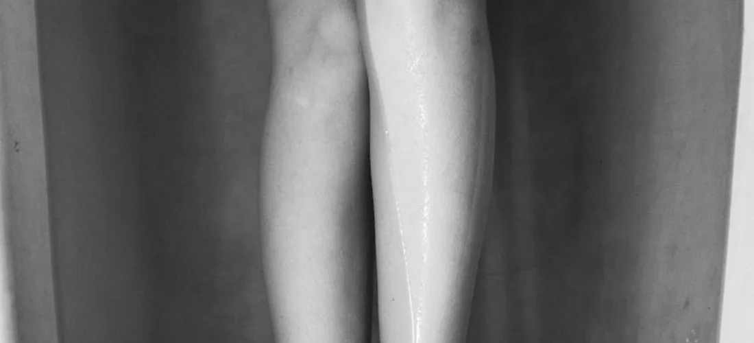 Close-up of two legs submerged in a bath or soaking tub, shown in grayscale