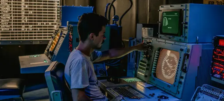 Technician seated at a console with multiple monitors and control panels in a lab-like setting, illustrating Jacuzzi maintenance mode and purification controls.