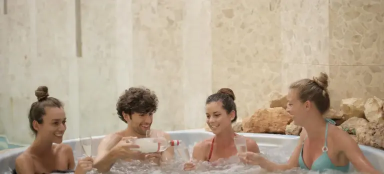 Four adults relaxing in a hot tub, smiling and chatting.