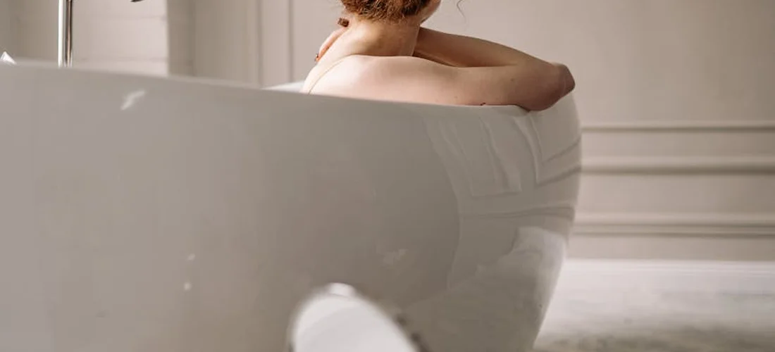 Person seated in a white walk-in bathtub, hands resting on the tub rim