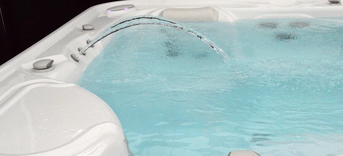 White whirlpool bathtub with built-in jets and a water fountain spout spraying water into the tub.