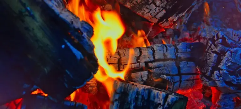Close-up of glowing flames and burning logs in a fire.