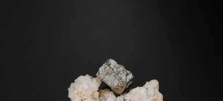 Close-up of a mineral cube resting on white rock against a dark background, illustrating mineral-based options in pool sanitation.