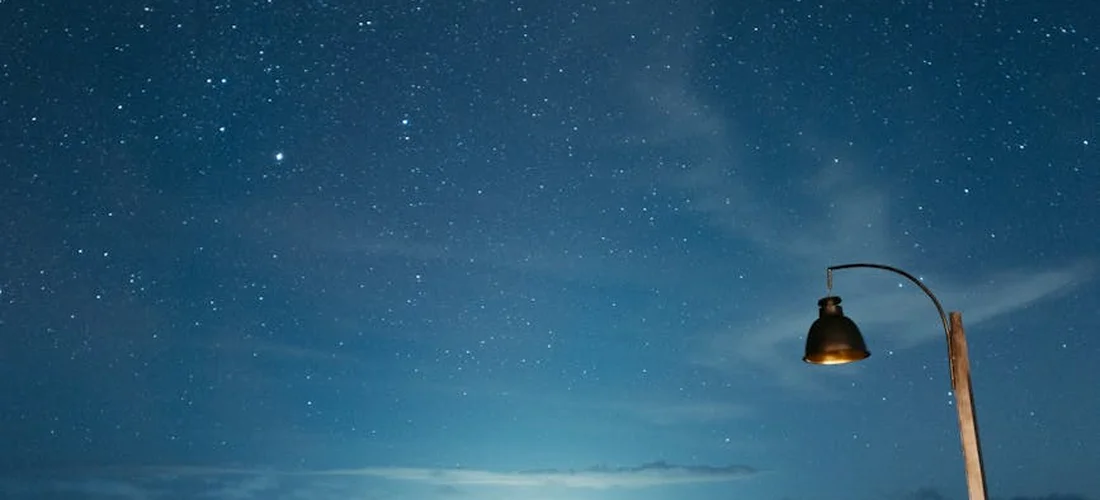 Star-filled night sky with a single street lamp on the right.