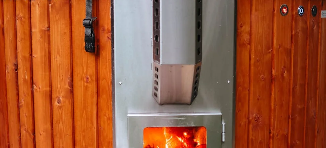 Outdoor metal utility cabinet mounted on a wooden fence with an orange glow inside.