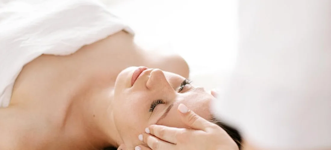 A person lying down with eyes closed, receiving a facial or spa treatment