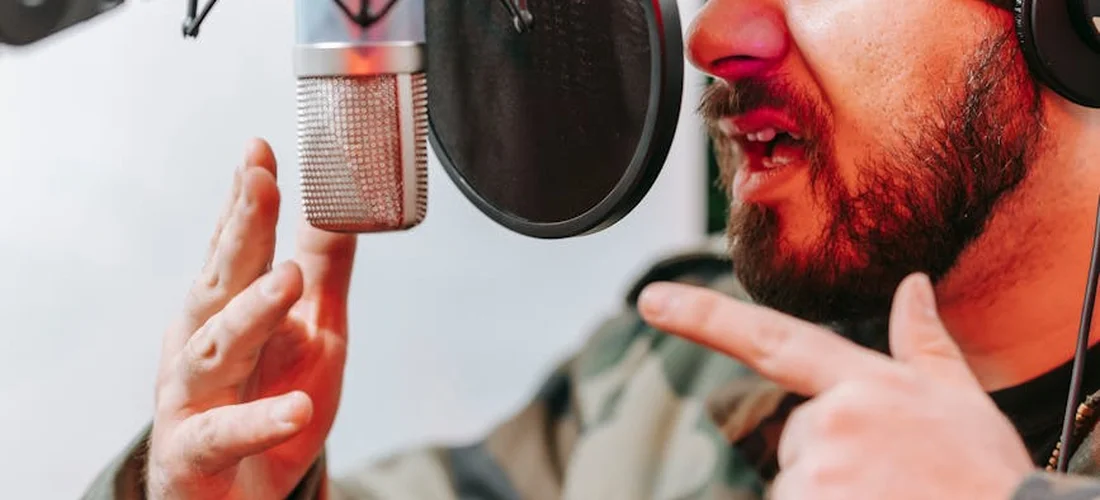Close-up of a person speaking into a studio microphone with a pop filter, illustrating professional audio gear for reliable sound in damp environments.