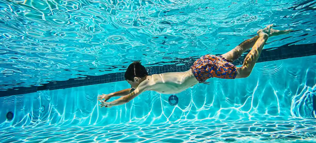 Underwater view of a person swimming in a clear blue pool