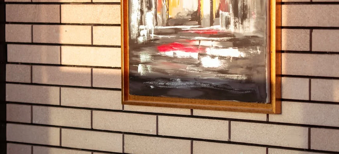 Framed painting hanging on a brick wall