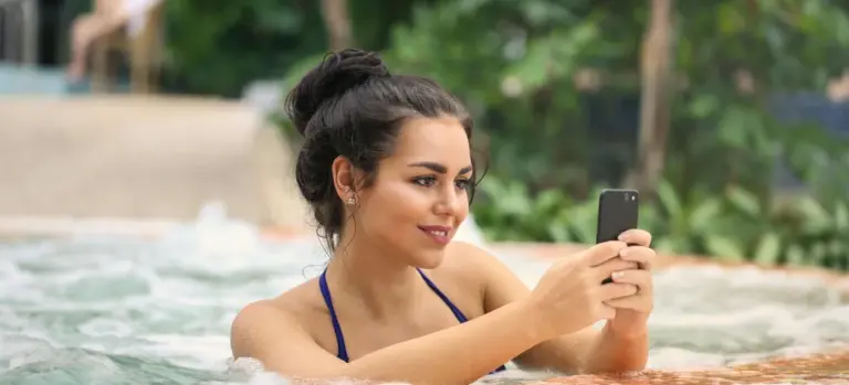 Woman in a hot tub holding a smartphone