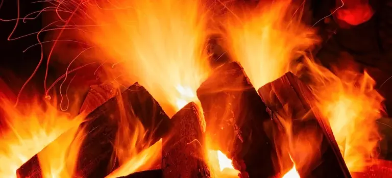Close-up of a wood-burning fireplace with bright flames and glowing embers